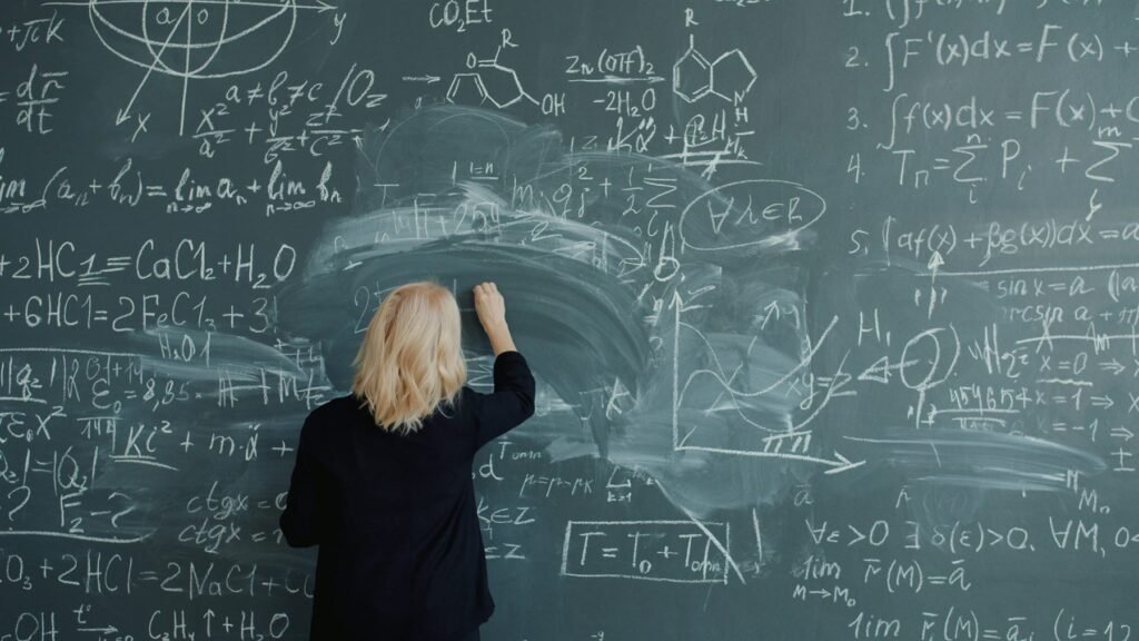 A teacher writing equations on a chalkboard during a lesson