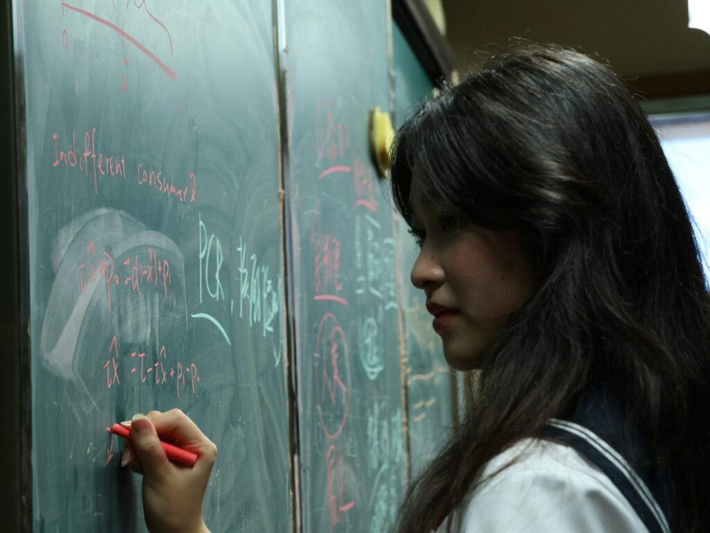 A senior high school student working through problems on a chalkboard during revision